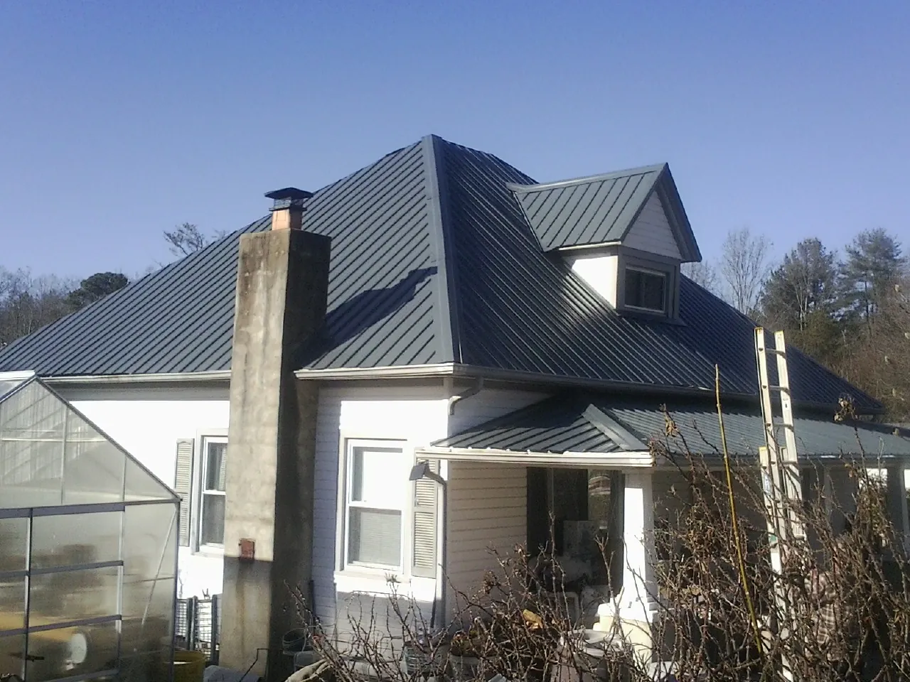 Dark blue standing seam metal roof on a white farmhouse with dormer — Slate & Tile Roof Repair by Roofing Brothers in Great Barrington
