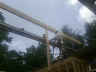 Carpenter setting a ridge beam over a new addition frame — Ice Dam Removal by Roofing Brothers in Great Barrington