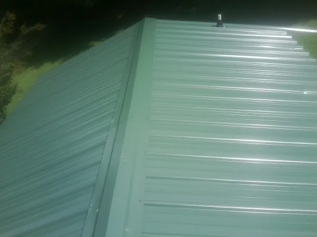 New green metal panels meeting at the ridge of a roof — Flat Roof Repair work by our crew in Great Barrington