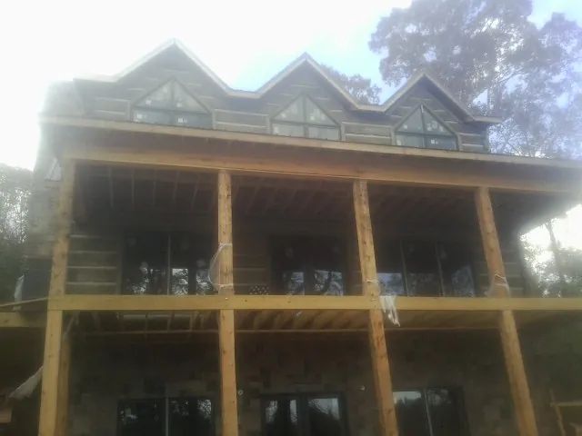 Dormers and porch framing on a large log home under construction — Roof Coating work by our crew in Great Barrington