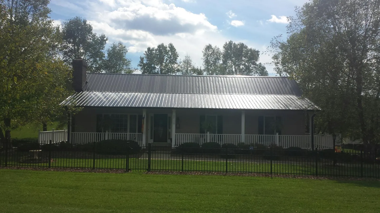 Gray metal roof on a brick ranch with a full width front porch — Gutter Guard Installation work by our crew in Great Barrington